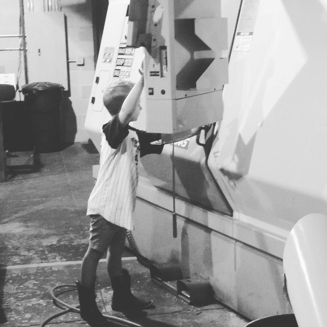 A young boy in cowboy boots reaching up to the controls of a Haas CNC machine