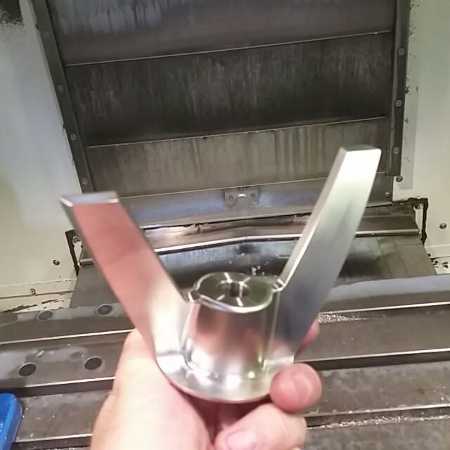 Machined stainless part held in front of a Haas machine